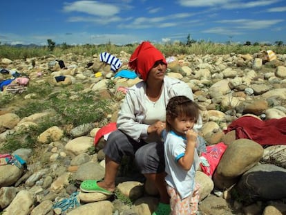 Una mujer y su hija lavan ropa en el río Táchira.