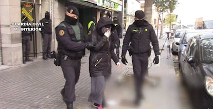 Dos agentes trasladan a una detenida por captar yihadistas, en Cataluña.