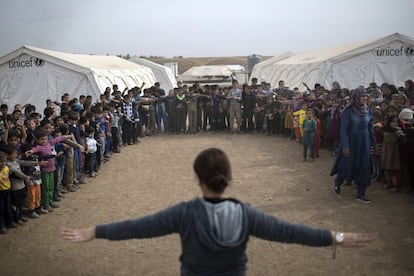 Niños iraquíes siguen las instrucciones de un profesor, durante una clase al aire libre en el campamento Hassan Sham, al este de Mosul (Irak). 
