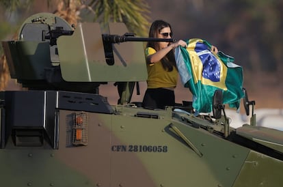 Una manifestante muestra una bandera nacional brasileña subida a un vehículo blindado del ejército durante una manifestación de apoyo a Bolsonaro, en Brasilia.