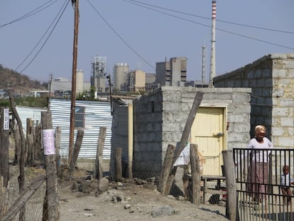 Una mujer con su hijo en uno de los asentamientos informales de los trabajadores de las minas de Marikana, en Sudáfrica. Este tipo de construcciones son el lugar de vida de los mineros y sus familias, pese a que la empresa Lonmin se comprometió a construir 5.500 viviendas en un documento legalmente vinculante.