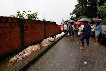 Un grupo de personas observa tres cadáveres recuperados en la zona de Morro dos Prazeres, Río de Janeiro.