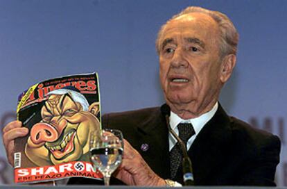 Peres muestra una revista sarcástica que lleva en portada una caricatura de Sharon, caricaturizado como un cerdo junto a una esvática.