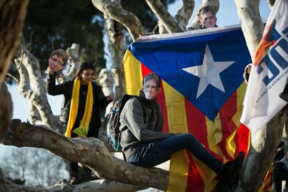 Dos manifestantes independentistas con caretas de Puigdemont se suben a un árbol durante las protestas por el aplazamiento de la sesión de investidura.