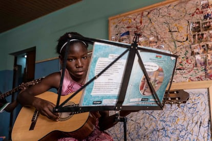 Una de las siete alumnas de clases de guitarra, con edades entre 9 y 15 años. El profesor de guitarra, Pascal, tiene 16 años y es un antiguo alumno de la escuela. 
En las culturas de tradición oral, como es el caso de Burkina Faso, en África del Oeste, la música y la danza están presentes en todos los rituales y momentos clave de la vida: como manifestación de lo profano o de lo sagrado, para vehicular mensajes sociopolíticos, históricos o amorosos, durante las cosechas, los ritos de iniciación o los encuentros sociales. En Burkina Faso existen alrededor de 60 grupos étnicos con diferentes tipos de instrumentos y melodías, constituyendo un rico elenco de expresión cultural. A este país, situado en el corazón de la franja del Sahel, llegó María Behrens, una violinista alemana hace 10 años y creó la Asociación Musical para los Niños del Mundo (AMEM), la primera escuela donde los instrumentos de cuerda clásicos flirtean con los instrumentos tradicionales del país. 