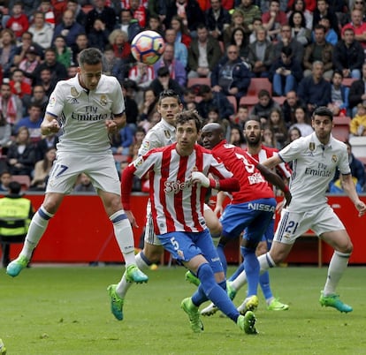El delantero del Real Madrid Lucas Vázquez (i) cabecea el balón ante los jugadores del Sporting de Gijón.