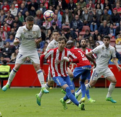 El delantero del Real Madrid Lucas Vázquez (i) cabecea el balón ante los jugadores del Sporting de Gijón.