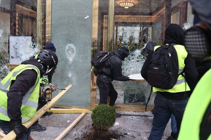 Un grupo de radicales rompen las ventanas de un establecimiento en el centro de París durante la protesta de los 'chalecos amarillos', este sábado.