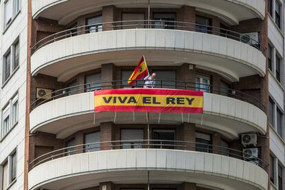 Un hombre coloca una bandera de españa, en apoyo a la monarquía, en el balcón de su casa en Valencia.