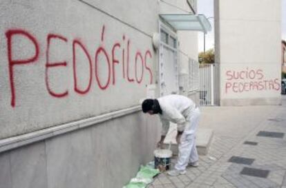 A painter begins to remove spray-painted messages in San Juan María Vianney parish, Granada.