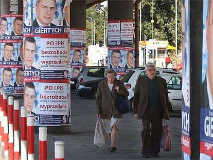 Dos transeúntes circulan por una calle de Varsovia empapelada con propaganda electoral.