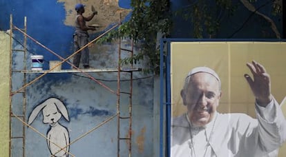 Un obrero repara un muro junto a un cartel del Papa.