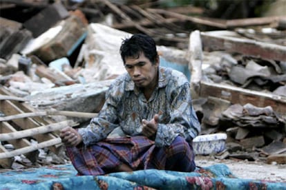 Un hombre reza sobre los escombros de su vivienda en Bantul.