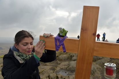 Una mujer toca la cruz situada donde San Patricio, según la leyenda, se sentaba para cuidar de su rebaño de ovejas, en Slemish Moutain, en Irlanda del Norte.