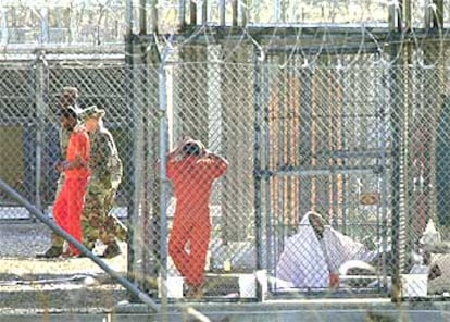 Soldados de EE UU conducen a un preso de la  base de Guantánamo, ante la mirada de otro, en marzo de 2002.
