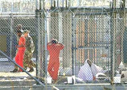 Soldados de EE UU conducen a un preso de la  base de Guantánamo, ante la mirada de otro, en marzo de 2002.