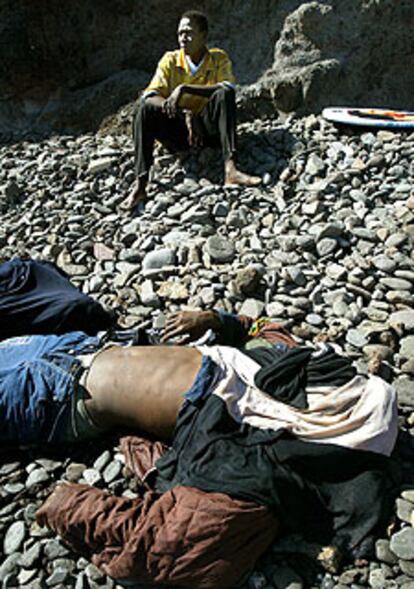 Un africano espera asistencia junto a dos cadáveres, el sábado, en Fuerteventura.