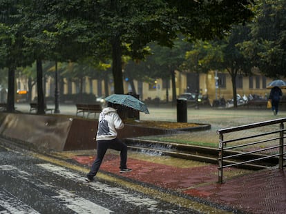Un peatón cruza una calle entre una fuerte tromba de agua en Pamplona, el sábado.