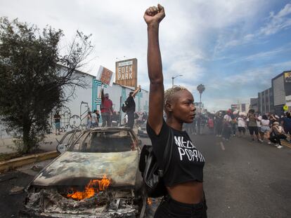 Una mujer posa delante de un coche de policía incendiado, el pasado sábado durante una protesta en Los Ángeles.