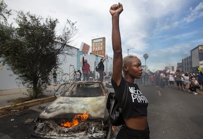 Una mujer posa delante de un coche de policía incendiado, el pasado sábado durante una protesta en Los Ángeles.