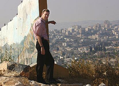 Uri Bank, junto al muro de Gilo, contempla la aldea palestina de Beit Yala. En la otra imagen, Meir Turjeman junto a los sacos terreros que protegen la entrada de una guardería.