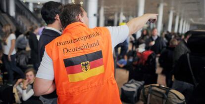 Un empleado de la delegación diplomática alemana conversa con un hombre junto a un grupo de unos 150 ciudadanos alemanes que se encuentran en el aeropuerto de El Cairo, Egipto.