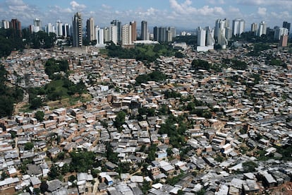 A large favela (slum) in São Paulo, with luxury apartment buildings in the background.