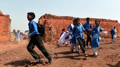 Niños paquistaníes van de camino a casa tras acudir a la escuela en las afueras de Lahore, ciudad de Pakistán.