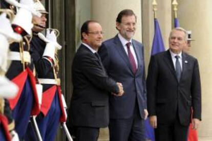El presidente del Gobierno español, Mariano Rajoy (c), estrecha la mano de su homólogo francés, Fraçois Hollande (i), en presencia del primer ministro francés, Jean-Marc Ayrault, a su llegada al palacio del Elíseo para asistir a la XXII cumbre bilateral celebrada en París, Francia, hoy.