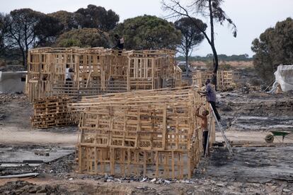Varios jóvenes reconstruyen las chabolas del asentamiento quemado el pasado día 16, en la localidad onubense de Palos de la Frontera.