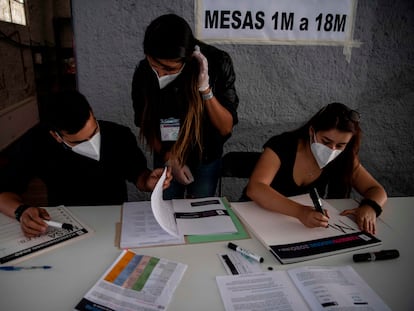 Membros do Serviço Eleitoral chileno preparam um ponto de votação em Santiago, horas antes do início do plebiscito deste domingo.