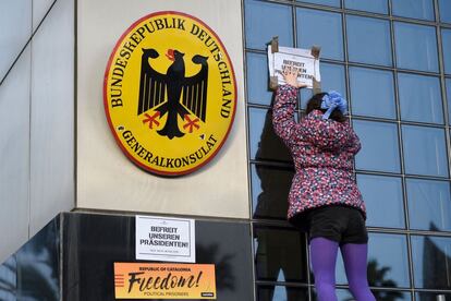 Una niña pega un cartel que dice en alemán "Libere a nuestro presidente" en el edificio del consulado germano, durante la manifestación que se celebra en Barcelona después de que el ex presidente de Cataluña fuera arrestado por la policía alemana.