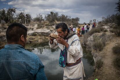 Un hombre wixárika bebe agua de una fuente sagrada durante el peregrinaje.