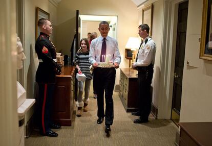 2 de dezembro de 2013. Com a filha do chefe de gabinete, Denis McDonough, Obama leva um bolo de aniversário para surpreender a McDonough em seu escritório de West Wing, na Casa Branca.