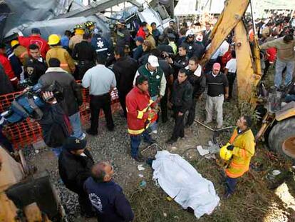 El cuerpo de una de las víctimas yace cubierto por una sábana en el lugar del accidente.