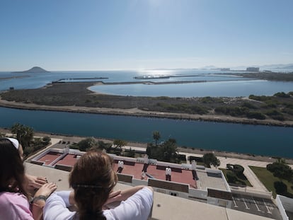 Dos personas contemplan el puerto inacabado desde su vivienda el viernes pasado.