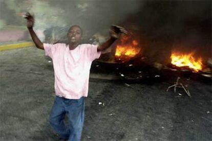 Un joven haitiano, ante una barricada levantada por seguidores de René Préval en Puerto Príncipe, ayer.