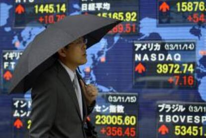 Un peatón pasa por delante de una pantalla con los resultados de la Bolsa de Tokio.