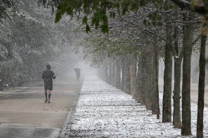 Un hombre corre bajo la nieve en el Parque del Retiro.