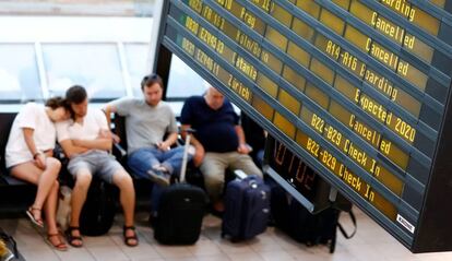 Pasajeros junto a un panel de vuelos del aeropuerto de Berlín