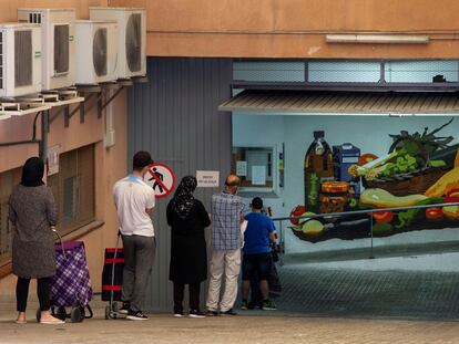 Varias personas, a la espera de recoger alimentos en el almacen de la Cruz Roja en Mataró (Barcelona).