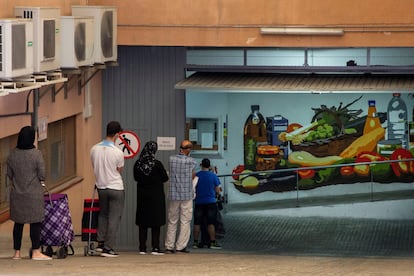 Varias personas, a la espera de recoger alimentos en el almacen de la Cruz Roja en Mataró (Barcelona).