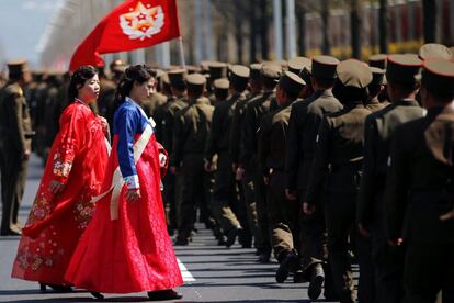 Dos mujeres pasan al lado de una fila de militares después de la inauguración.