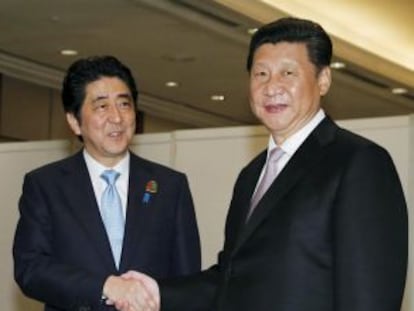 El primer ministro japonés Shinzo Abe (izquierda) da la mano al presidente chino Xi Jinping este miércoles en Yakarta.