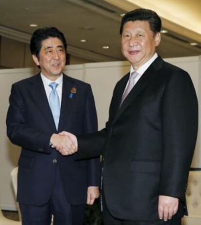 El primer ministro japonés Shinzo Abe (izquierda) da la mano al presidente chino Xi Jinping este miércoles en Yakarta.
