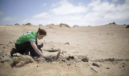 Una voluntaria recoge plásticos llegados a través del mar.