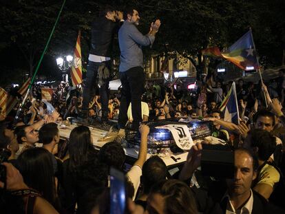 Jordi Cuixart y Jordi Sànchez, subidos en el techo de un vehículo policial durante la protesta multitudinaria contra el registro de la Consejería de Economía, el 20 de septiembre de 2017.