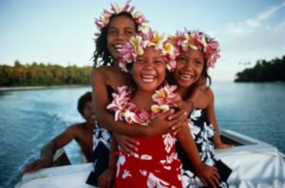 Tres niñas con diademas de flores en una embarcación en las islas Cook.