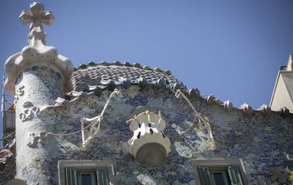 Part superior de la façana de la Casa Batlló que s'acaba de restaurar, amb les cadenes daurades al costat de les grues per pujar mobles.
