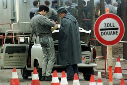 Un ciudadano del Este alemán muestra el 24 de noviembre de 1989 las pertenencias que transporta en su automóvil en la plaza de Postdamer a un oficial vestido con el traje de los agentes del Este.